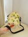 butterfly print polyester shoulder handbag, yellow with green butterflies, woman holding smaller bag in hand on yellow countertop