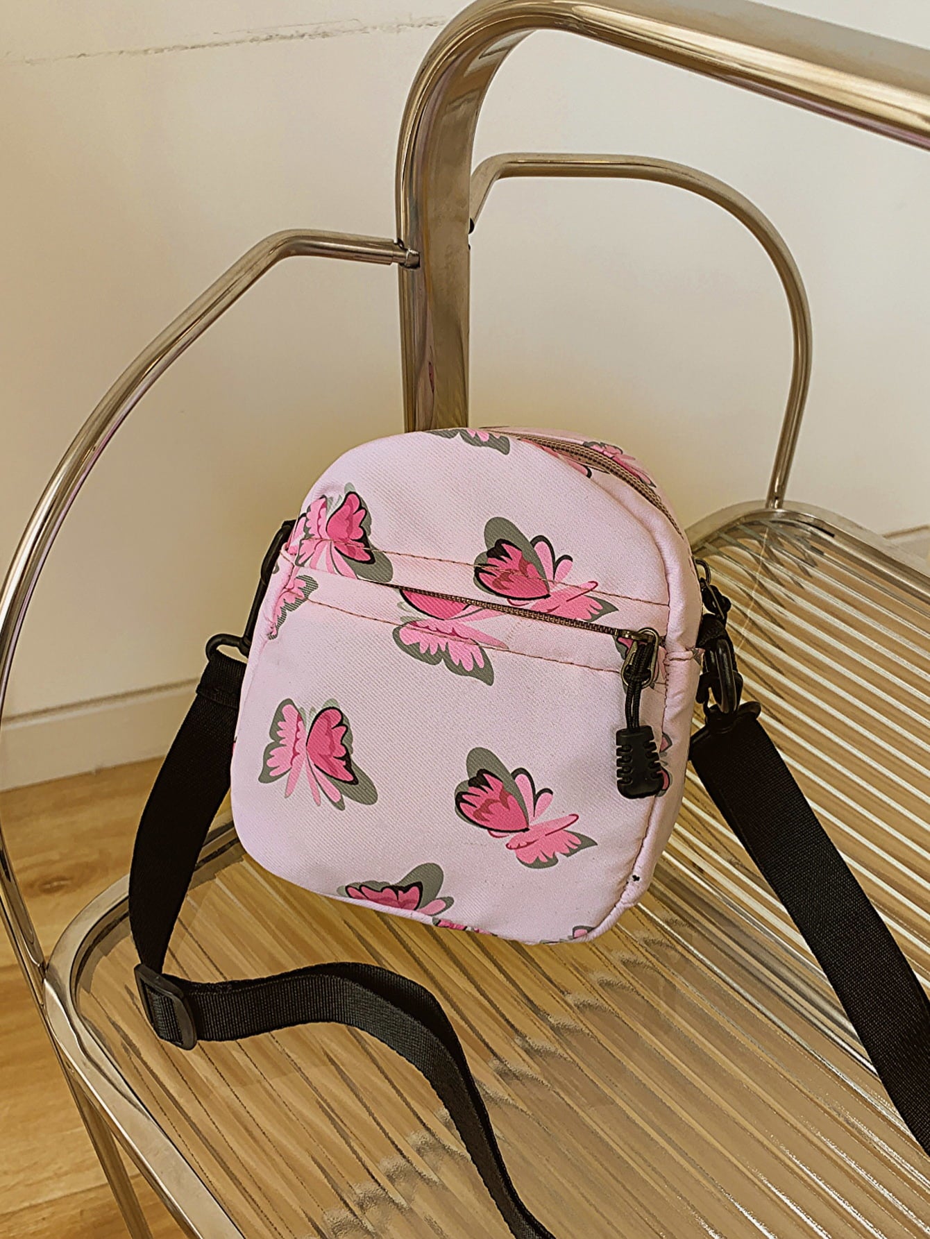 butterfly print polyester shoulder handbag, pink with pink butterflies, on metal slatted chair