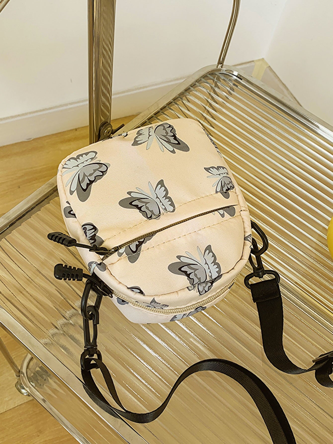 butterfly print polyester shoulder handbag, yellow with gray butterflies, on glass and metal slatted cart