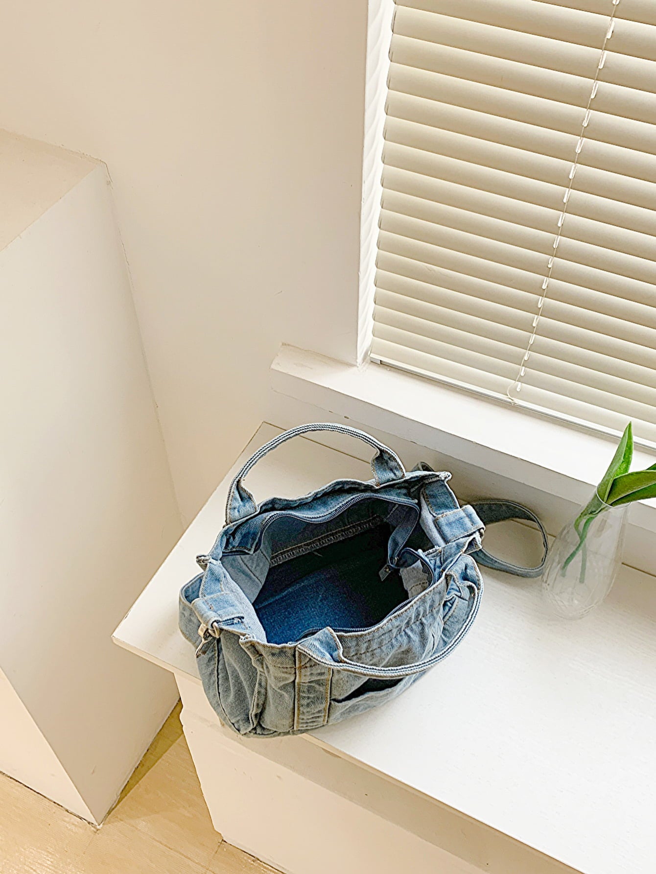 denim shoulder handbag, light blue, top-down interior view, on a white countertop