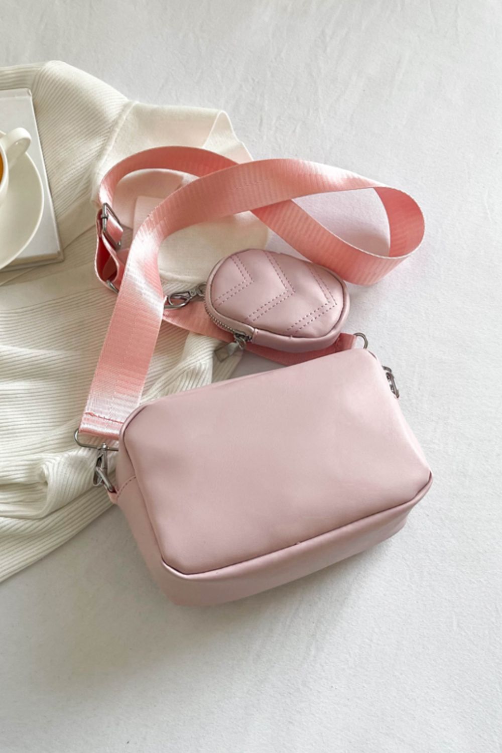 pu leather shoulder bag with small purse, blush pink, back view, handbag on floor on top of white sweater
